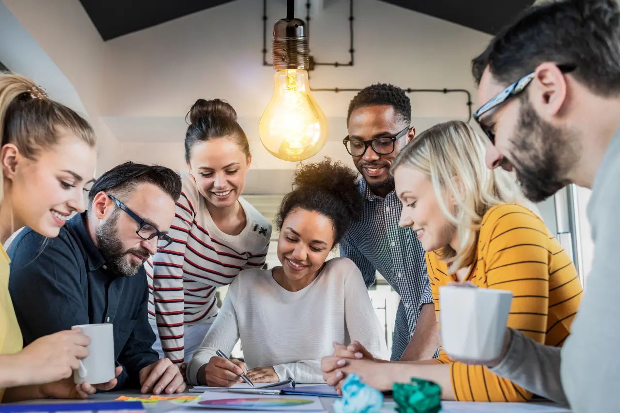A imagem apresenta um grupo de jovens multiétnico que está em uma sala de reuniões reunidos em um trabalho. O tema do artigo é curva de inovação.